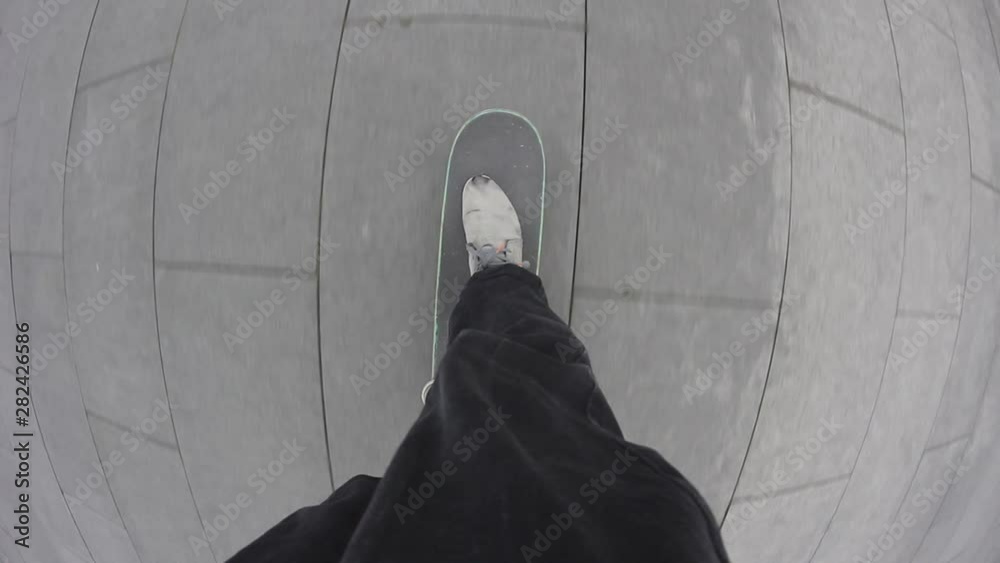 Point of view of skateboarder riding skateboard on the city sidewalk. Skater rolling freestyle in urban environment. Young man holding balance on board, extreme sport