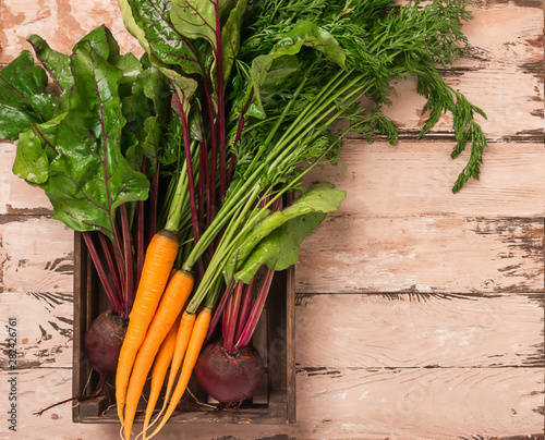 Fresh organic beets and carrots in a crate wooden background. Autumn summer harvest concept. Top view. Natural style. photo