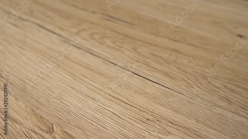 Closeup of the wood floor newly installed. Floor is made of the natural oak hard wood and sanded and finished with natural clear flooring stain. Home improvement and remodel concept in slow motion.