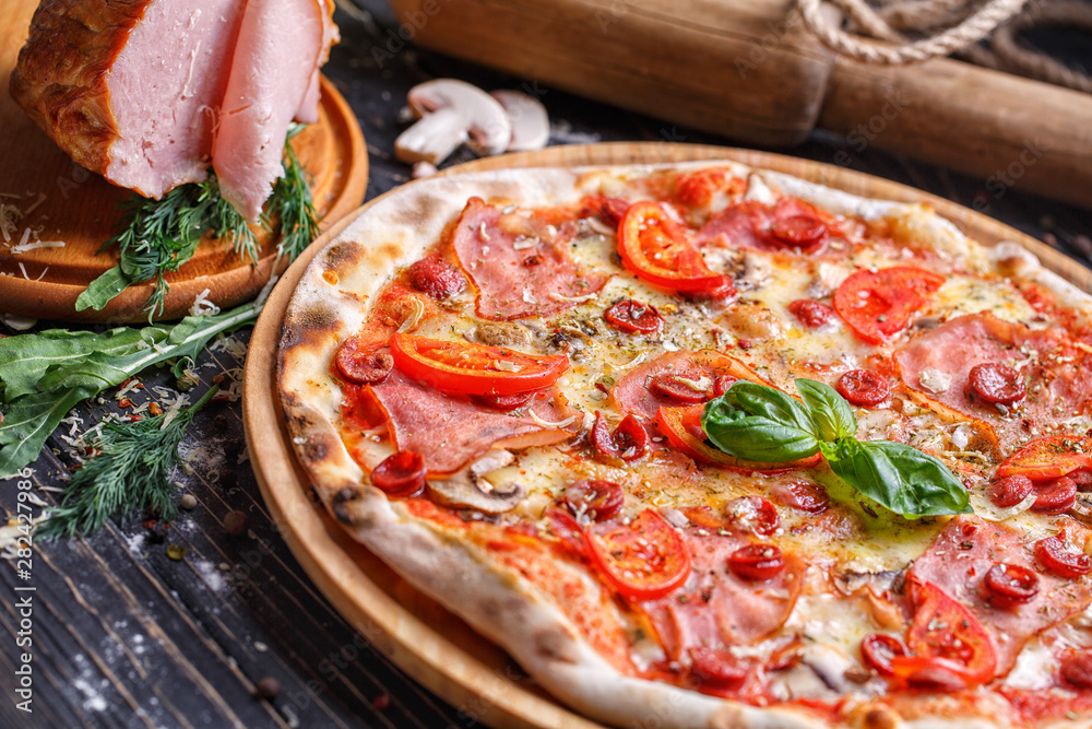 Aromatic pizza with sausage and tomatoes is decorated with basil Aromatic pizza with sausage and tomatoes is decorated with basil