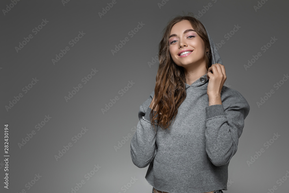 portrait of smiling woman with perfect skin and long hair in gray sweater on dark background. girl looking at camera. copy space portrait of smiling woman with perfect skin and long hair in gray sweater on dark background. girl looking at camera. copy space
