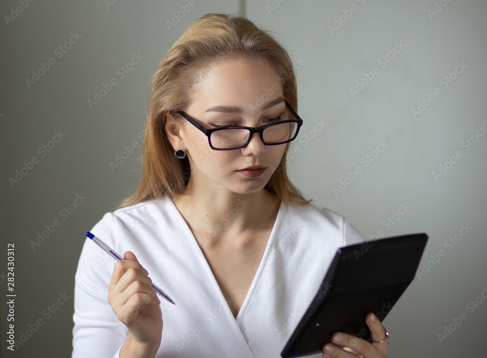 Portrait of the young business woman with calculator and pen