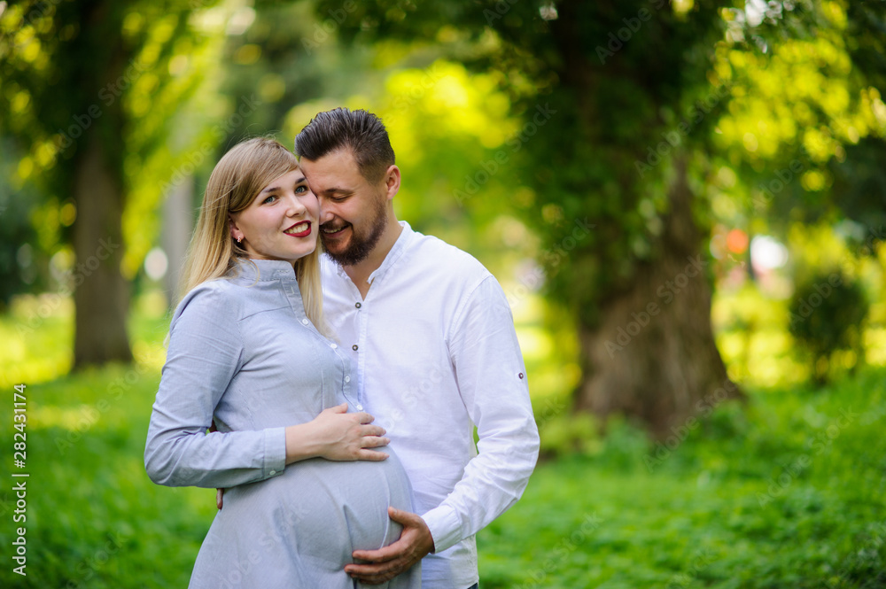 Happy and young pregnant couple hugging outdoor