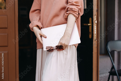 Woman holding laptop and pink sunglasess in outdoor. Social media concept. Freelancer. Blogger