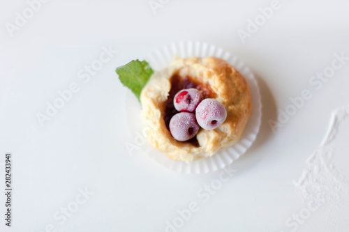 Homemade pastries with berries, powdered sugar and mint leaves. Baked cookies on table. Buns on white background.