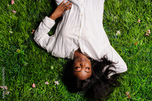 Portrait of beautiful african american woman laying on green grass in park
