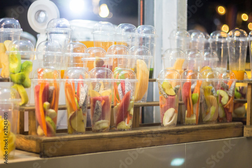 Different kinds of fruits in plastic glasses for making smoothies.