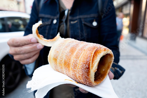 Photography man eating a typical Czech trdelnik in Prague