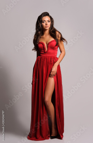 gorgeous woman in red dress. Studio picture, grey background