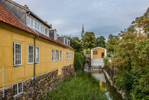 Canal along a yellow building at the scenic town Frederiksvaerk, Denmark photo