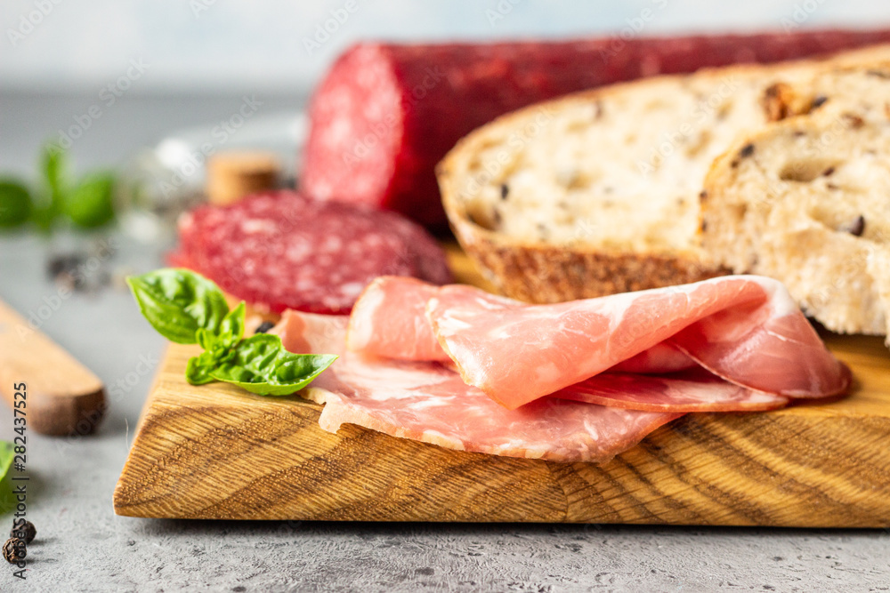 Traditional artisan bread with seeds and pork sausage and salami served on a wooden cutting board. Open sandwich with pork sausage. Traditional artisan bread with seeds and pork sausage and salami served on a wooden cutting board. Open sandwich with pork sausage.