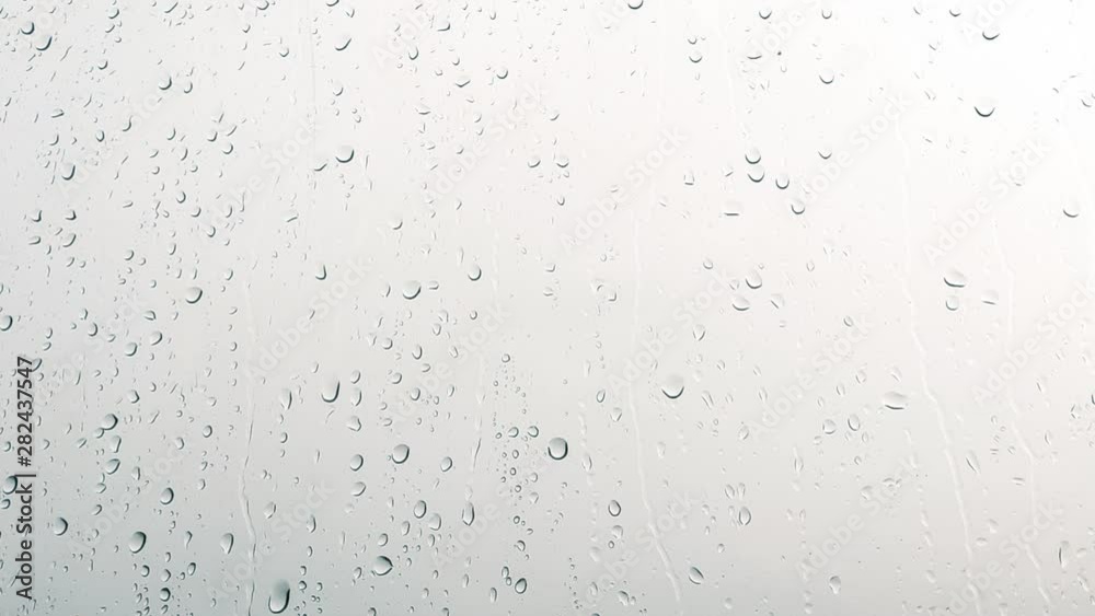 Close-up of water droplets on glass, Rain Rain, Go Away. Large rain drops strike a window pane Close-up of water droplets on glass, Rain Rain, Go Away. Large rain drops strike a window pane