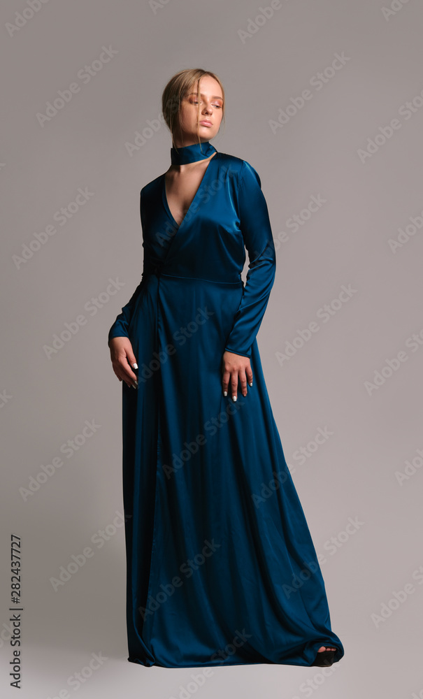 Pretty girl in green dress. Studio picture, grey background