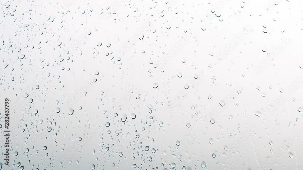 Close-up of water droplets on glass, Rain Rain, Go Away. Large rain drops strike a window pane