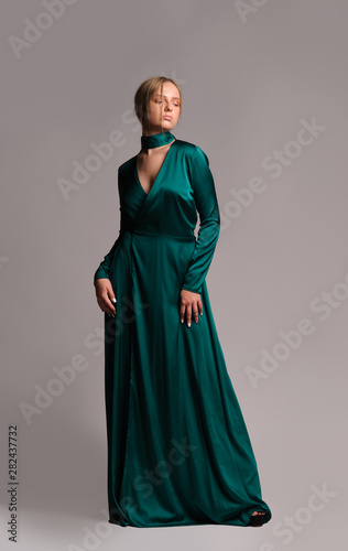Pretty girl in green dress. Studio picture, grey background