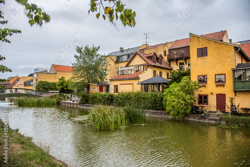 a picturesque canal with bulrush along old yellow houses