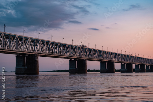 Fototapeta Naklejka Na Ścianę i Meble -  Bridge over the Amur river at sunset. Russia. Khabarovsk. Photo from the middle of the river.