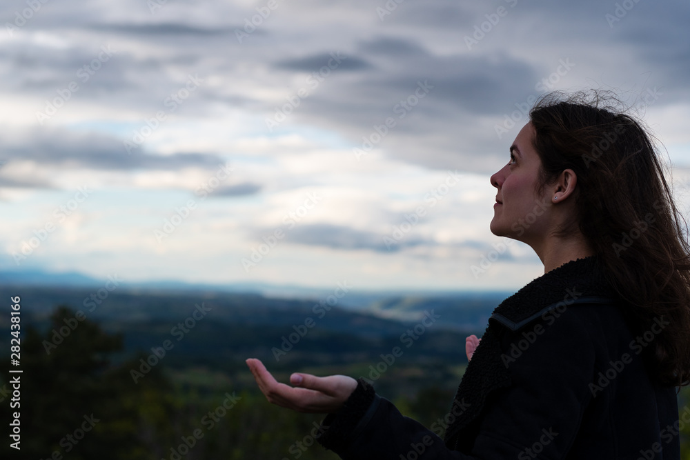 Naklejka premium Christian worship and praise. A young woman is praying and worshiping in the evening.