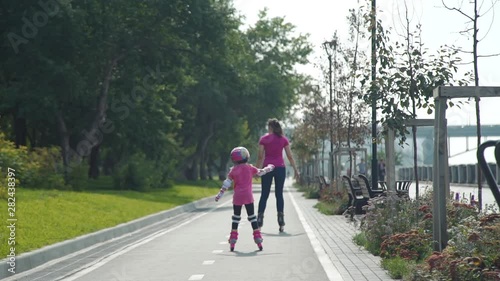 Wallpaper Mural Little Girl Rollerblading with her Mother in the City Street in Sunny Day in Slow Motion. Back view. Summer Family Activities Concept Torontodigital.ca