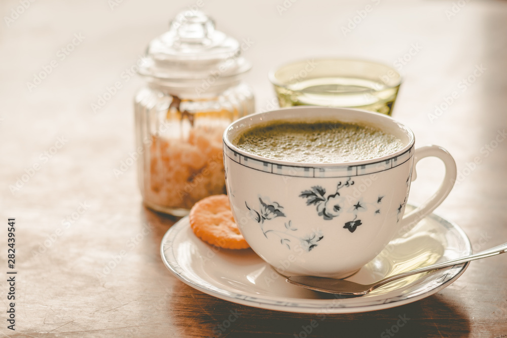 green tea matcha soy latte in a china cup with brown sugar and a glass of water on the side green tea matcha soy latte in a china cup with brown sugar and a glass of water on the side