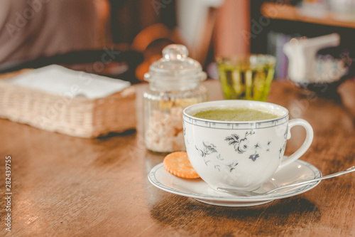 green tea matcha soy latte in a china cup with brown sugar and a glass of water on the side