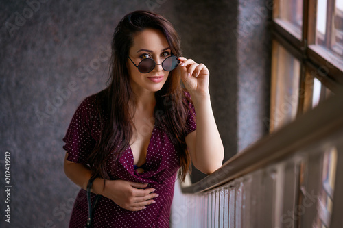 beautiful young pregnant woman standing on the stairs with glasses
