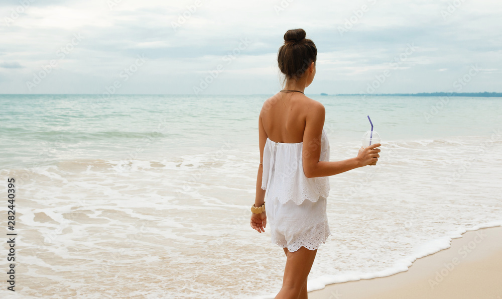 Beautiful woman wearing white jumpsuit walk on the beach Beautiful woman wearing white jumpsuit walk on the beach