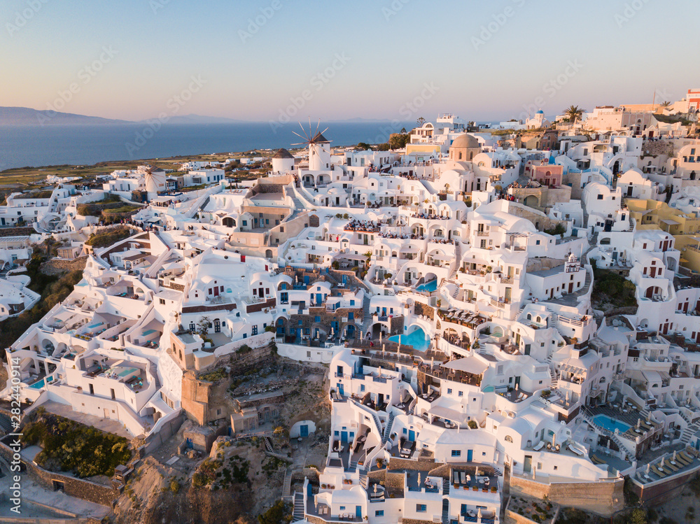 Aerial view of Santorini island, Greece, Oia village with windmills and white houses. Amazing sunset view of romantic island from quadcopter.The most romantic place for a wedding.