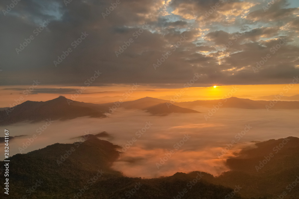 Mountain view morning of top hill around with sea of mist in valley with orange sun light and cloudy sky background, sunrise at Pha Tang, Chiang Rai, northern of Thailand.