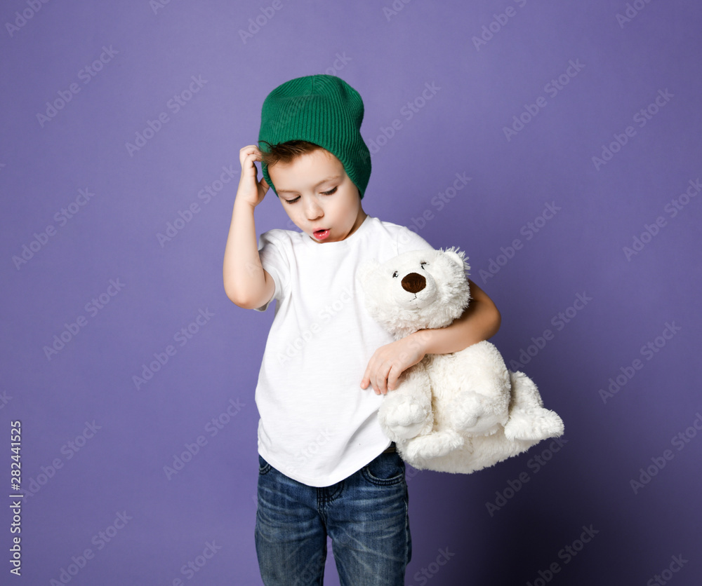 Young concerned kid boy child in green hat holding his polar bear toy. International day of polar bear concept Young concerned kid boy child in green hat holding his polar bear toy. International day of polar bear concept