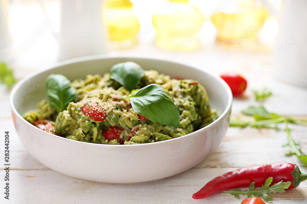 Pasta with spinach and tomatoes. A dish on a white wooden table Pasta with spinach and tomatoes. A dish on a white wooden table