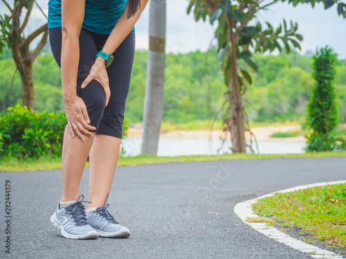 woman runner sports injured leg and knee pain at garden. © Apichet
