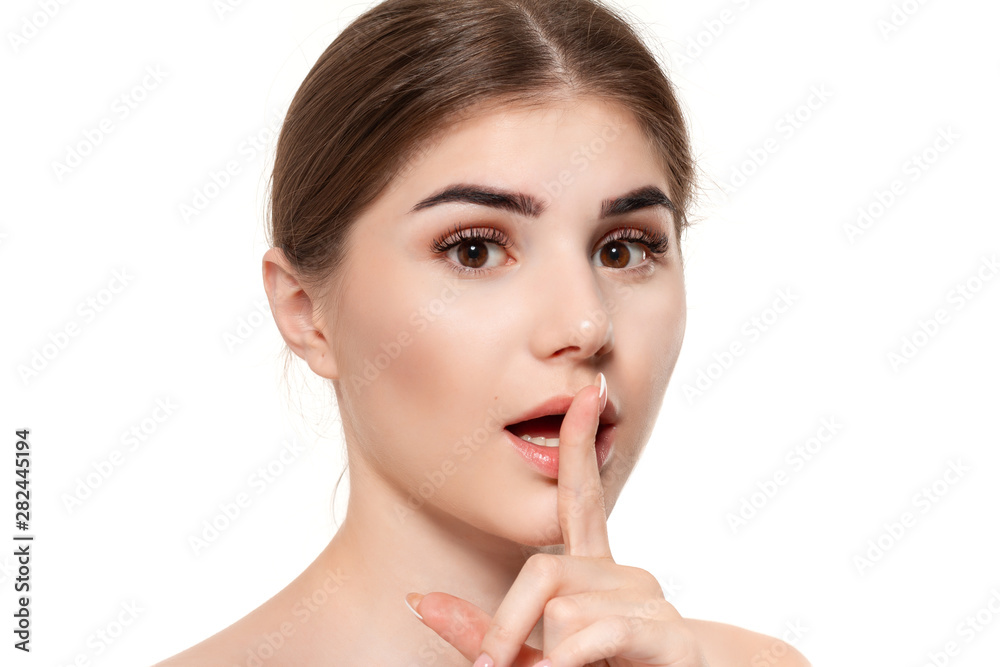 Close-up portrait of a beautiful young girl holding finger near her mouth expressing idea of secret isolated over white background. Close-up portrait of a beautiful young girl holding finger near her mouth expressing idea of secret isolated over white background.