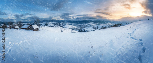 amazing panoramic view of rural village and mountains on horizon covered with snow on sunset. beautiful winter landscape © ver0nicka