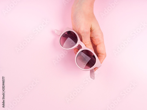 Pink sunglasses in woman's hand