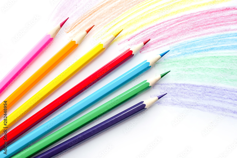 Fototapeta premium Color pencils with rainbow drawing isolated on white background. Top view.