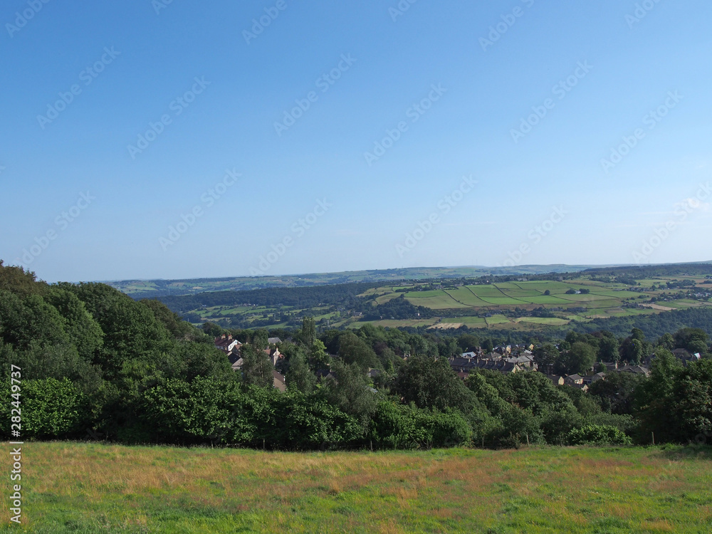 a panoramic view west yorkshire countryside with the village of warley surrounded by woodland and farmland with pennine hills in the distance