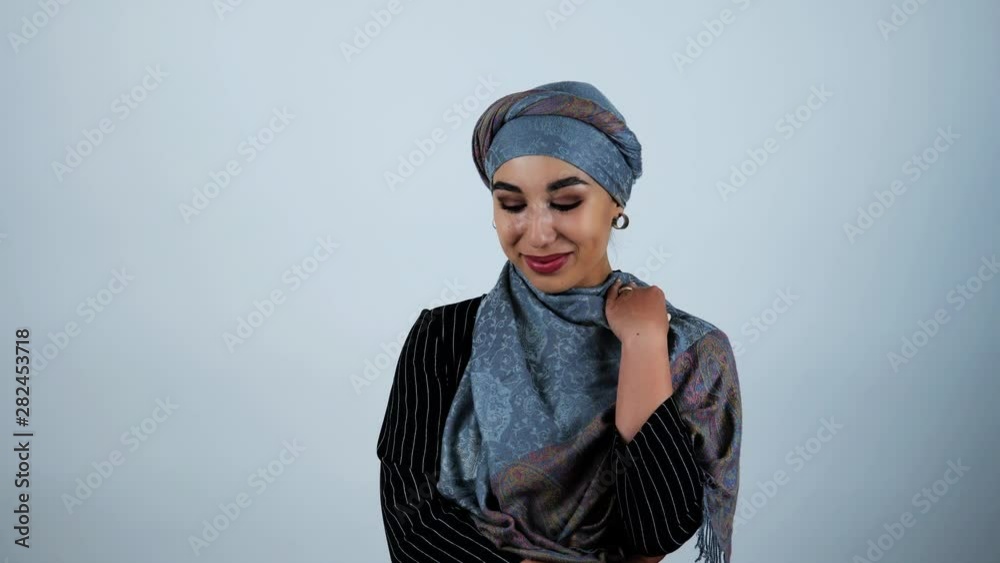 young beautiful arabic woman smiling adjusting her headscarf with her hand moving on isolated white background young beautiful arabic woman smiling adjusting her headscarf with her hand moving on isolated white background