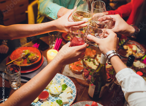 Fotografia Human hands with glasses of red wine clinking them over served table