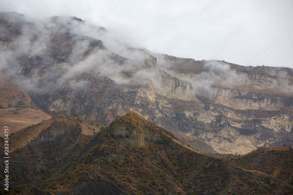Picture of mountains with trees, smoke, gray sky by day