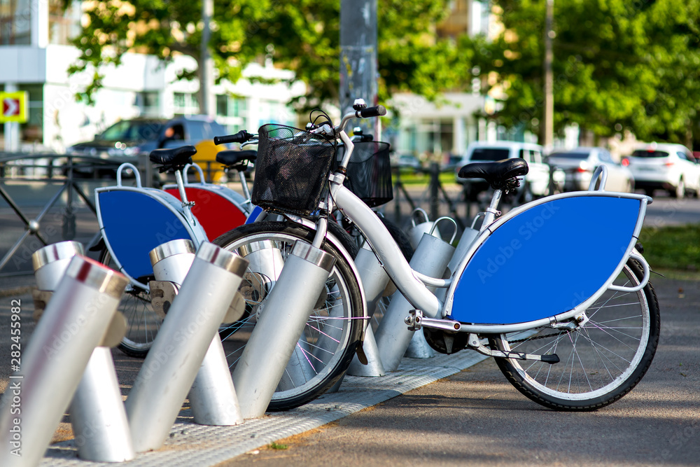 Obraz premium bike rental in a city park on the background of the road with traffic jam, rental bike gray with blue advertising space.