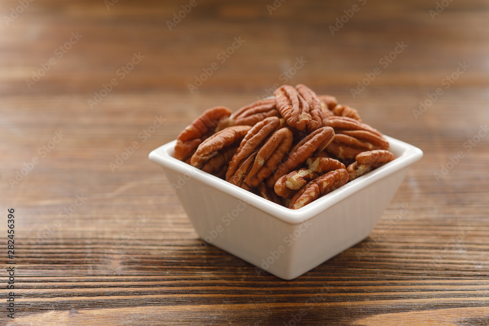 Fototapeta premium White square bowl of pecan nuts. Healthy eating concept