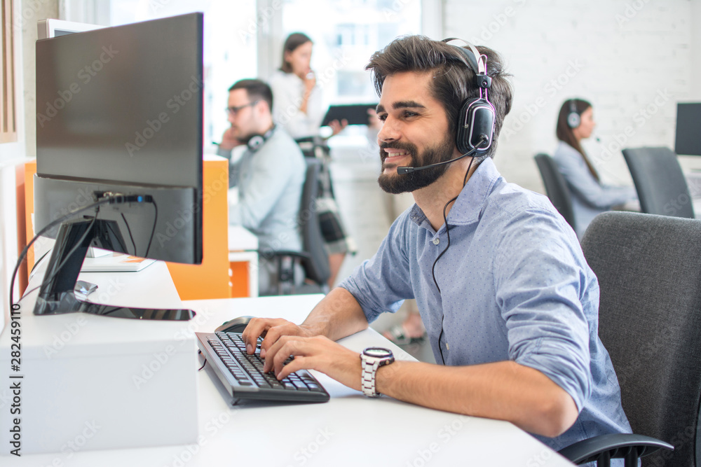 Young handsome man wearing headset working on computer in call center Young handsome man wearing headset working on computer in call center