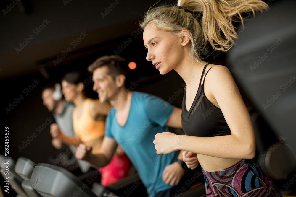 Young people using threadmill in modern gym Young people using threadmill in modern gym