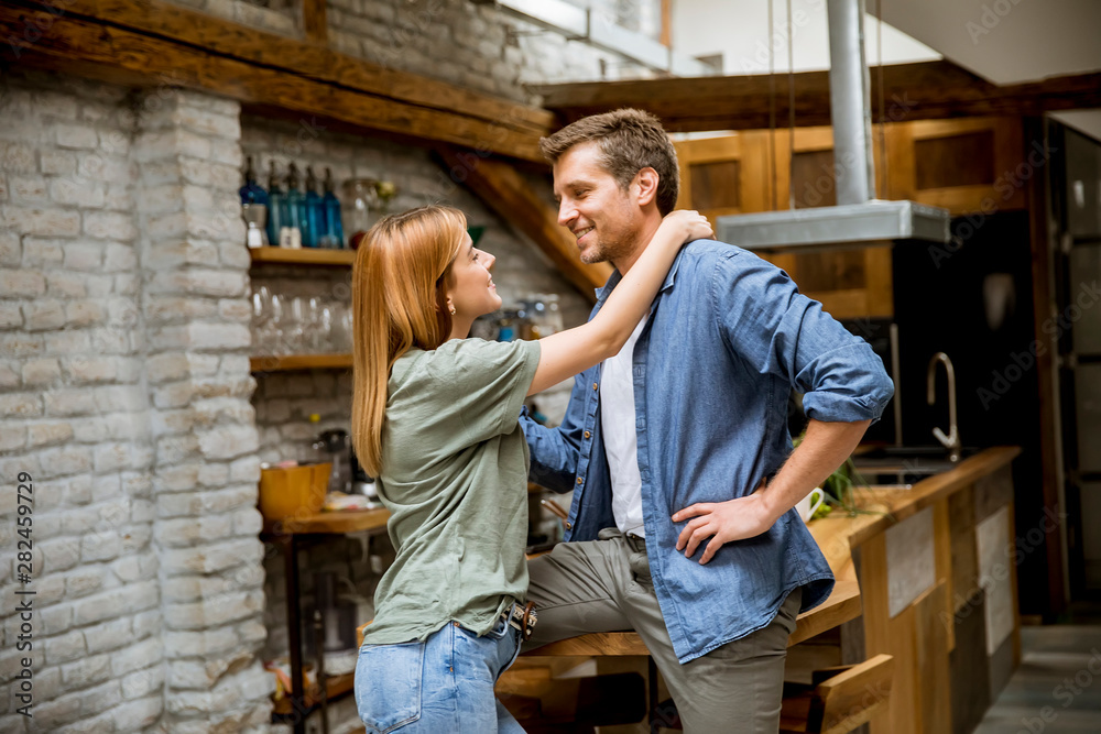 Cute young couple hugging while cooking in their kitchen