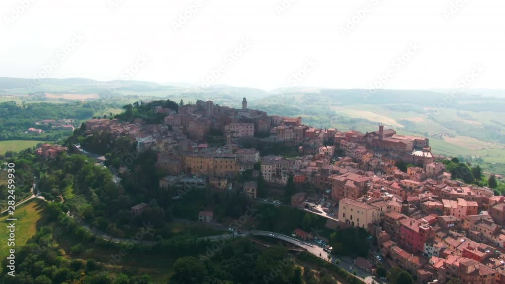 Traveling in Tuscany. Aerial view of majestic hilltop city of Montepulciano on sunny day. Amazing medieval red cityscape in green landscape highland. Italian dream destination.