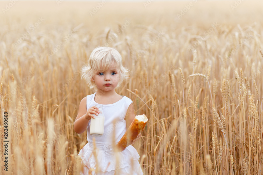 Happy child holding bread in hands. Portrait of a little girl in the wheat field. Children with bread and milk. Little girl in cereal field. Happy child holding bread in hands. Portrait of a little girl in the wheat field. Children with bread and milk. Little girl in cereal field.