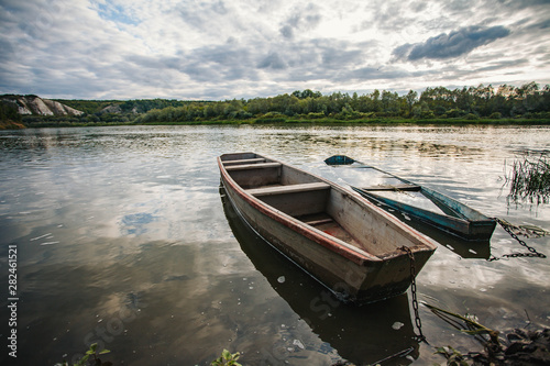 Fototapeta Naklejka Na Ścianę i Meble -  abandoned old wooden fishing boat near pier in summer lake or river. beautiful summer sunny day or evening.