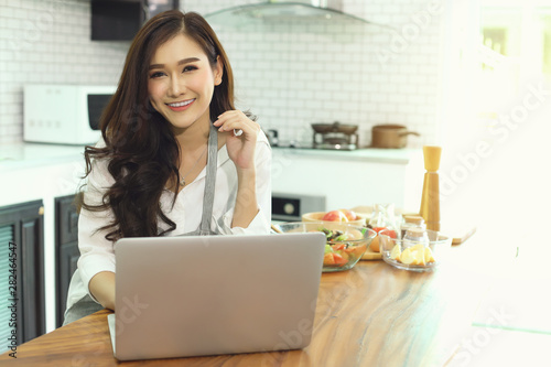 Asian girl in the kitchen She works at home through the internet..Modern woman concept © boonchok