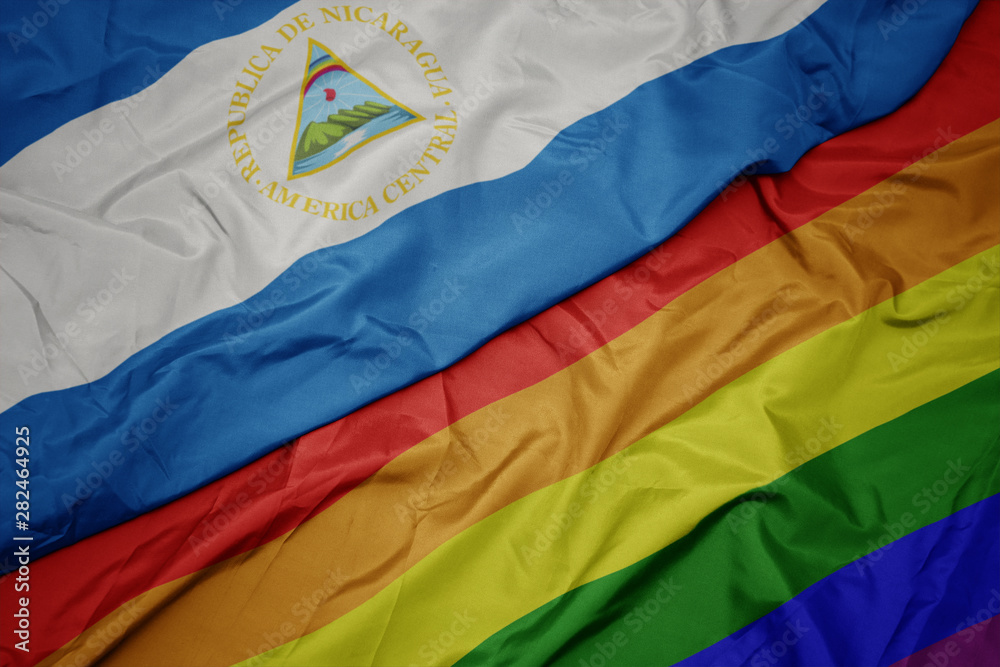 waving colorful gay rainbow flag and national flag of nicaragua.